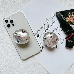 Detailed view of silver lava-textured phone grip with colorful gemstones on a white phone