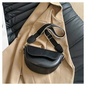 Détail du sac selle noir avec logo doré et bandoulière en tissu pour femmes