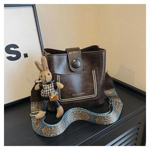 Detail of dark brown bucket bag featuring ethnic wide strap and cute rabbit pendant