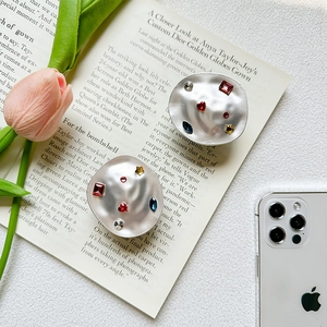 Detailed view of metal phone grip with colorful rhinestones on a magazine background