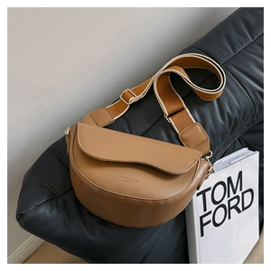 Gros plan détaillé du sac selle marron avec bordure ondulée et bandoulière tissée large