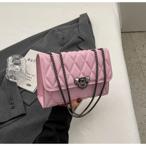 Dettaglio borsa a tracolla trapuntata rosa con catena su una giacca grigia elegante
