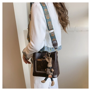 Detail of dark brown bucket bag featuring ethnic print strap and cute rabbit pendant