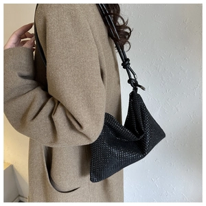 Detail einer schwarzen Glitzer-Schultertasche kombiniert mit einem Wollmantel