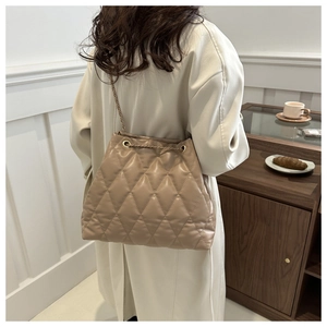Quilted beige bucket bag detail featuring golden chain strap and rhombus stitching texture