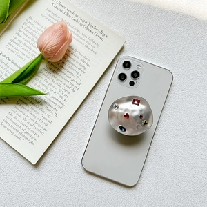 Foldable metal phone grip with colorful gemstones and red heart on white mobile phone