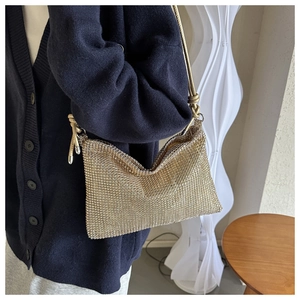 Nahaufnahme einer modischen goldenen Schultertasche mit funkelndem Strass-Effekt