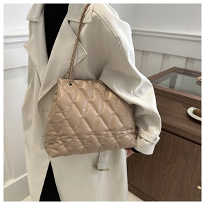 Quilted tote bag detail with gold chain strap on model wearing beige trench coat