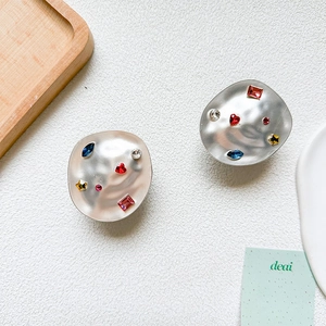 Close-up of matte silver irregular round stud earrings with colorful crystal rhinestones