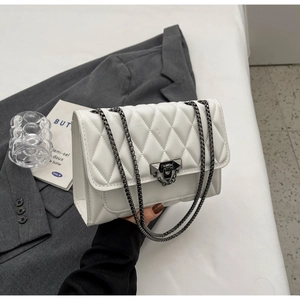 Dettaglio della borsa a tracolla bianca trapuntata con catena e fibbia in metallo scuro