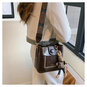 Brown leather bucket bag detail with bohemian strap and plush bunny pendant on model