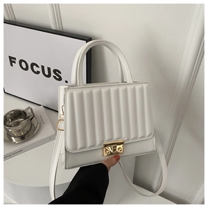 Vue détaillée de la texture matelassée verticale et du fermoir doré de ce sac blanc chic