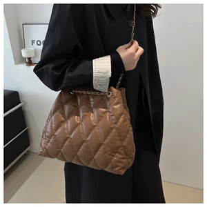 Detailed view of caramel brown quilted bucket bag with gold chain and diamond stitching