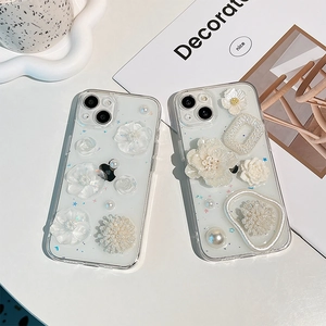 Transparent iPhone case with 3D floral accents and pearls on white minimalist background