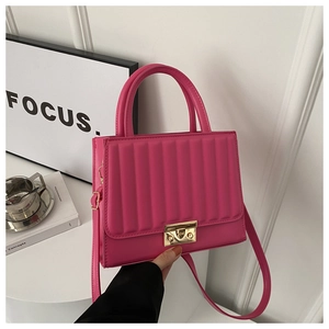 Détail du sac à main matelassé rose vif avec serrure dorée et motif à rayures verticales