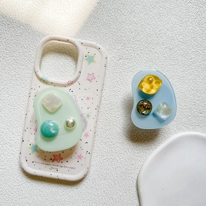 Detail of a pearl and turquoise gemstone phone grip with an irregular star pattern base