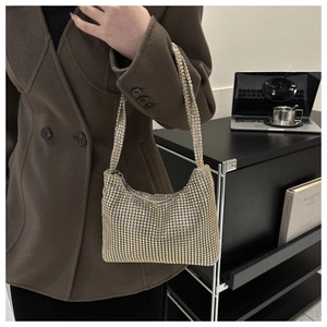 Golden rhinestone shoulder bag shown on model with a textured sparkling finish