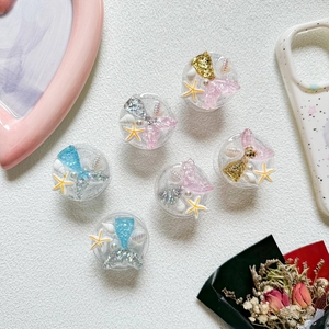 Detail shot of mermaid tail phone socket grips with glitter, pearls, and sea shells