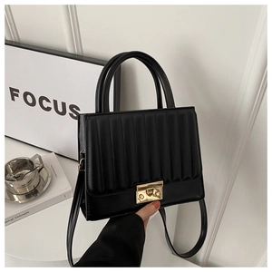 Détail d'un sac bandoulière plissé noir avec un fermoir métallique doré rectangulaire