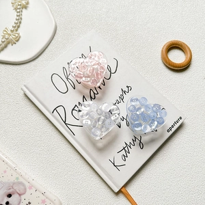 Close-up of heart-shaped phone grips with button inserts in pink, blue, and white colors
