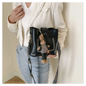 Detail of black glossy bucket bag with ethnic embroidery strap and bunny charm