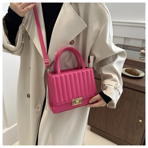 Detail of pink quilted handbag with gold square buckle and leather shoulder strap