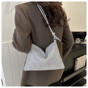 Silberne Strass-Schultertasche glänzt auf einem braunen Mantel für Party und Mode