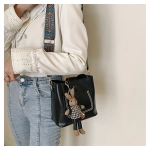Detail of black bucket bag with bohemian jacquard strap and plush rabbit charm