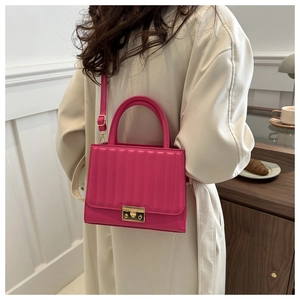 Détail du sac bandoulière plissé rose rouge avec boucle dorée sur fond minimaliste