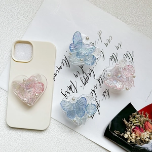 Macro detail of heart-shaped phone grip with resin 3D rose and pearl decorations