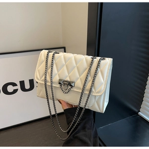 Detailed view of white quilted faux leather texture and metal chain clasp on handbag