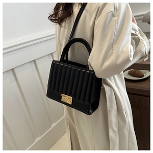 Détail du sac bandoulière plissé noir avec une boucle dorée rectangulaire sur blanc