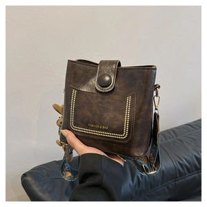 Close-up of vintage brown leather crossbody bag with colorful ethnic strap and bear charm