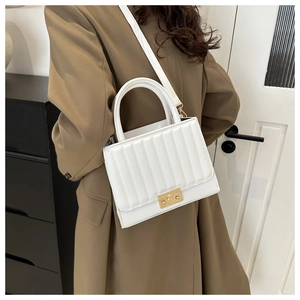 Détail d'un sac à main blanc avec plis verticaux et fermoir métallique rectangulaire doré