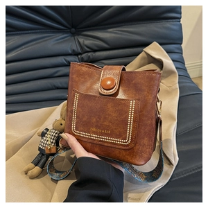 Detail of vintage brown oil wax leather bucket bag with bohemian printed wide strap