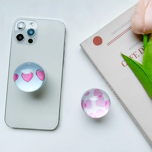 Macro view of crystal glass heart phone socket stand with pink heart patterns on white book
