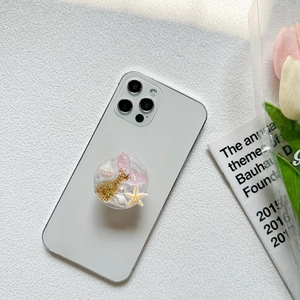 Ocean theme glitter phone grip with pink mermaid tail and shells on white smartphone