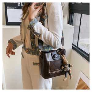Minimalist vintage dark brown PU leather bucket bag with stylish geometric strap and charm