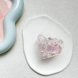 Macro detail of heart-shaped resin phone grip with 3D rose, butterfly and pearls