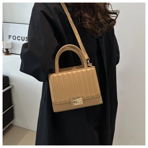Détail du sac en cuir marron clair avec rabat plissé vertical et fermoir en métal doré