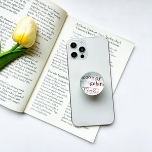 Minimalist round glass phone grip with red gelato cookie text on white smartphone