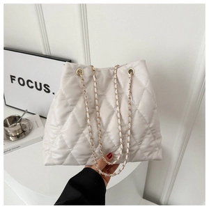 Gros plan sur le sac cabas matelassé beige avec bandoulière chaîne et cuir souple