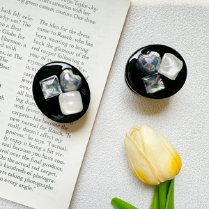Detail of luxury heart and square gem phone grip with iridescent finish on book background