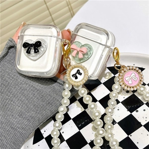 Transparent AirPods case with pearl strap and 3D bow heart design held in hand