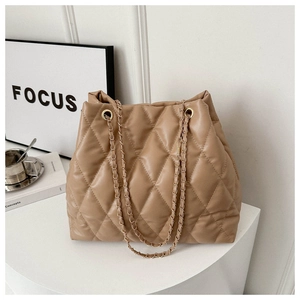 Detail of khaki quilted tote bag with metal chain strap on a white display stand