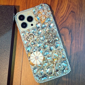 Luxury iPhone case with sparkling rhinestones, golden crown, and floral bow decorations