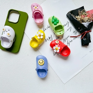 Colorful shoe-shaped phone stands with flower and smiley decorations on a desk