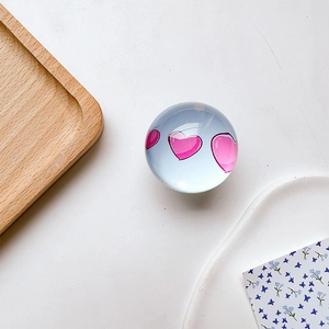 Detailed view of a transparent glass ball with pink hearts on a modern desk setup