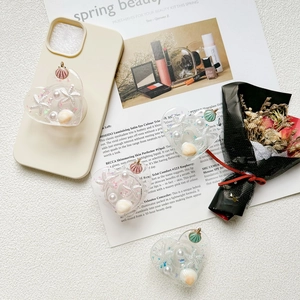 Détail du support de téléphone en cœur avec coquillages, perles et paillettes stylisé