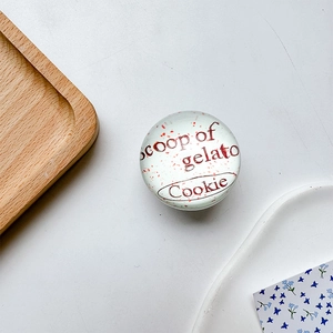 Macro shot of circular glass phone grip with red flake decor and gelato cookie text